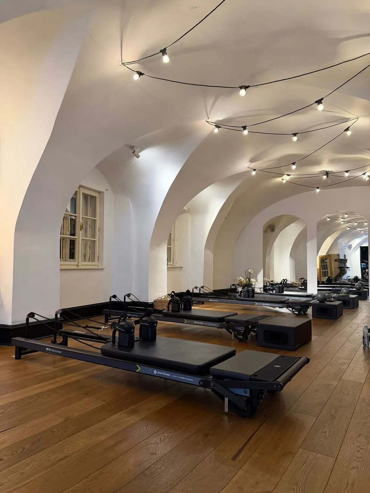 The ReformerX studio in the evening, string lights under the vaulted ceiling