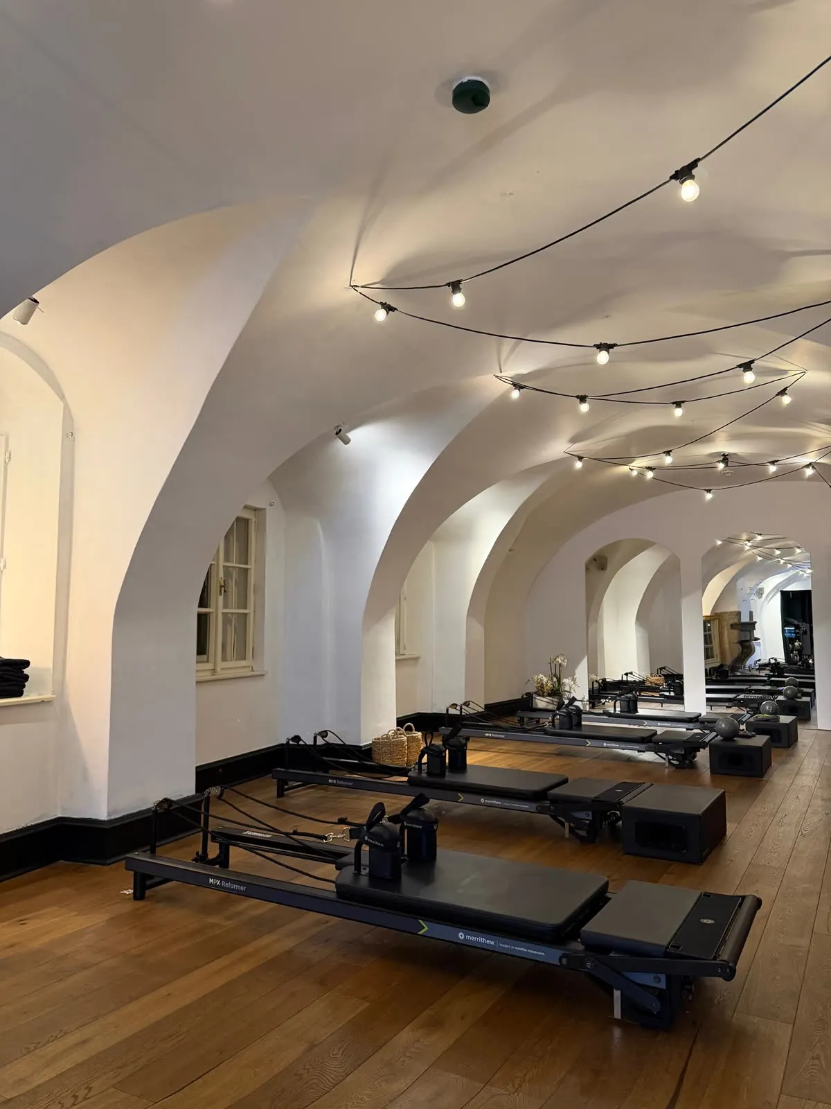 A row of reformers along the vaulted arches of the studio